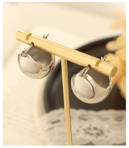 Close-up of minimalist silver spherical huggie earrings on a display stand