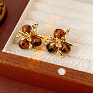 Vue macro de boucles d'oreilles vintage dorées avec perles œil de tigre dans un écrin