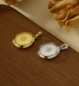 Close-up of gold and silver S925 sterling silver starburst oval locket pendants