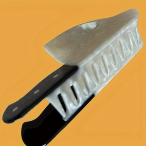 Detailed close-up of a kitchen knife shaped hair claw made of marbled acetate and black plastic