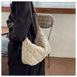 Beige quilted nylon crossbody bag with diamond stitch detail shown on model in natural light