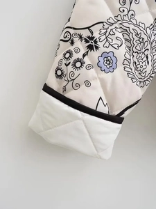 Close-up of quilted floral cotton jacket sleeve with black piped edges and paisley print