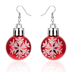 Close-up of red Christmas bulb earrings with white 3D snowflake patterns and silver hooks
