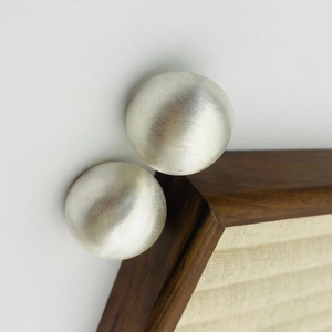Détail macro de boucles d'oreilles sphériques argentées avec texture brossée