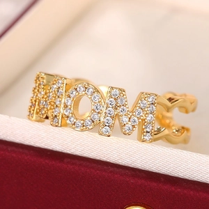 Macro shot of gold MOM ring with pavé pavé crystals and heart detail on jewelry box