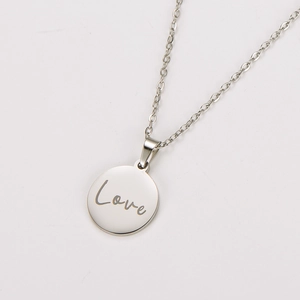 Gros plan d'un collier avec pendentif circulaire argenté et gravure Love en cursive élégante