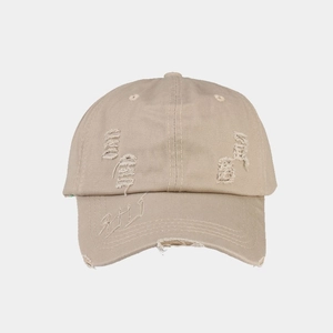 Detailed view of beige washed baseball cap with distressed finish and white embroidery