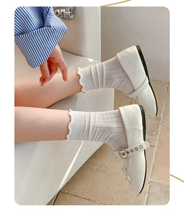 Detail of white ruffle socks with vertical stripes paired with Mary Jane shoes