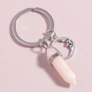 Detail of silver crescent moon charm and hexagonal pink crystal pendant on a keychain