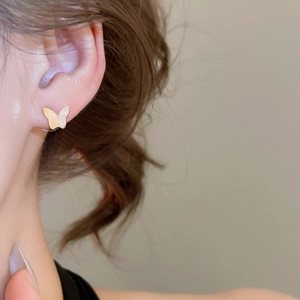 Detailed close-up of a butterfly ear stud with a gold base and elegant white wings