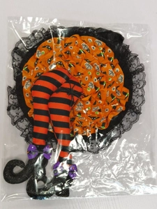 Macro detail of Halloween witch legs decoration with orange skirt and striped boots in package