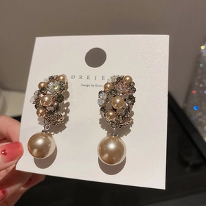 Macro detail of Korean style gold floral earrings with pearls and crystals