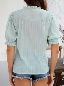 Detail of light green chiffon blouse with back pleats and ruffled bell sleeves