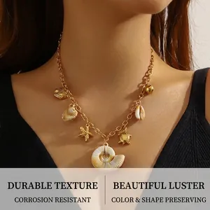Detail of gold ocean necklace with turtle, starfish and conch shell charms on model