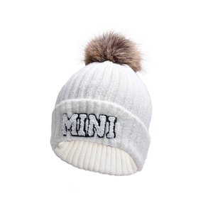 Close-up of white ribbed knit beanie with MINI embroidery and brown faux fur pom-pom