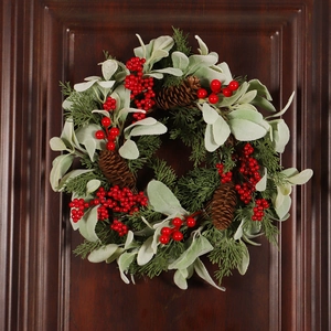 Artificial Christmas wreath with red berries, pine cones and flocked leaves on wooden door