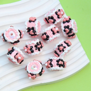 Detailed view of pink barrel beads with black flower patterns for DIY jewelry making