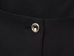 Detail view of premium black fabric featuring a polished gold dome metal button closure