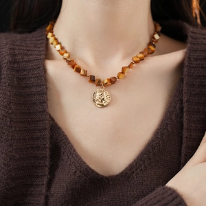 Detailed close-up of amber resin beads and a golden coin pendant with portrait relief