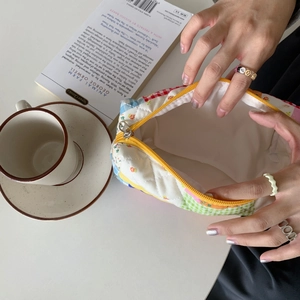 Vista dettagliata di una pochette trapuntata patchwork a fiori con cerniera gialla vivace