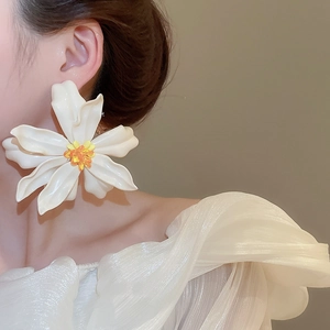 Detailed close-up of large white acrylic floral earring with yellow gradient center