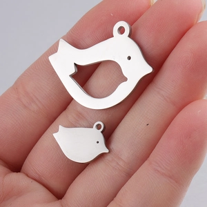 Macro view of mirror-finish stainless steel bird pendants on palm showing scale