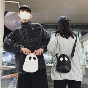 Detail of cute ghost-shaped PU leather crossbody bags in black and white worn by models