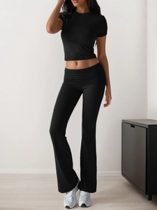 Detailed view of women black short-sleeve crop top and high-waisted flared yoga pants set