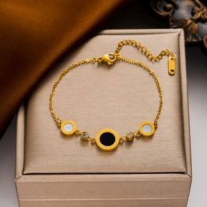 Elegant gold stainless steel bracelet with Roman numeral charms on a jewelry box