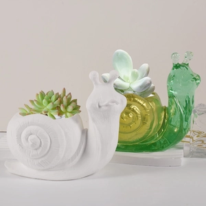 Detail view of snail-shaped mini succulent planters in white matte and green glass textures
