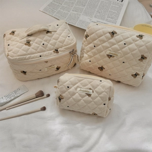 Detailed set of three beige corduroy pouches with bear embroidery and quilted texture