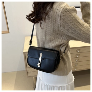 On-body view of a black saddle crossbody bag featuring a distinctive gold vertical lock