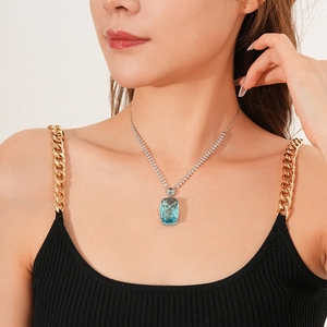 Detail of silver necklace with blue square zircon pendant worn by a professional model