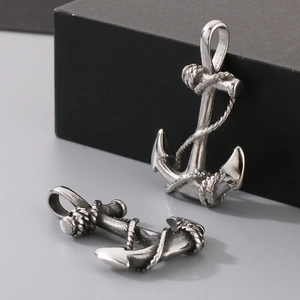 Detail of vintage silver anchor pendants with rope design on a black cube background