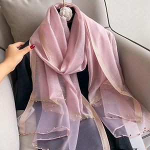 Detail view of pink silk scarf featuring elegant gold beaded edges and sheer texture