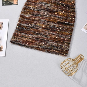 Dettaglio dell'abito in maglia a righe marroni con paillettes e morbida texture pelosa