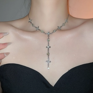 Silver Y-shaped cross necklace with sparkling crystal droplets worn by a female model