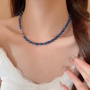 Close-up of beaded necklace with blue jade and red accents on model's neck
