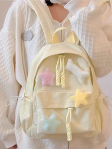 Close-up of light yellow nylon backpack with plush star charms and bone pendant details