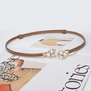 Fashionable brown leather belt with gold pearl buckle on a stylish magazine background
