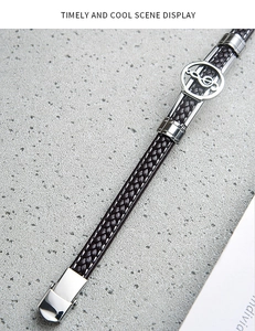 Close-up of men's black braided leather bracelet with silver musical note charm