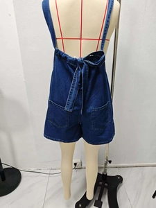 Detail view of denim romper back featuring large pockets and adjustable bow tie waist