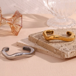 Detail of gold and silver irregular wave cuff bracelets with S925 engraving on stone