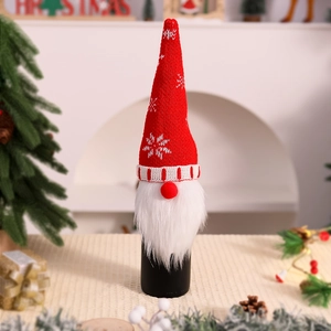 Detail of red knitted elf wine bottle cover with white beard in a festive Christmas setting