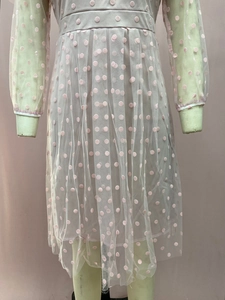 Detailed close-up of pink mesh dress with textured dots and contrasting white trim edges