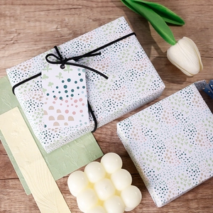 Pastel macaron floral gift wrapping paper on a box with white tulips and wooden background