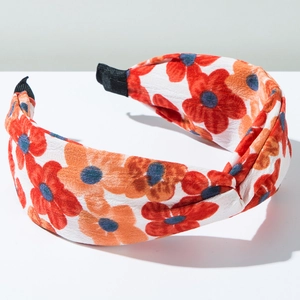 Détail d'un serre-tête large à fleurs avec nœud central et embouts antidérapants