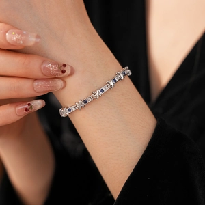Dettaglio del bracciale argento con zirconi blu e chiari dal design incrociato a X