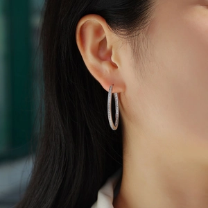 Macro shot of silver hoop earrings set with small moissanite stones on a female model