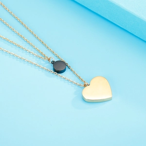 Dettaglio dei ciondoli a cuore dorato e cilindro nero su catena a due strati